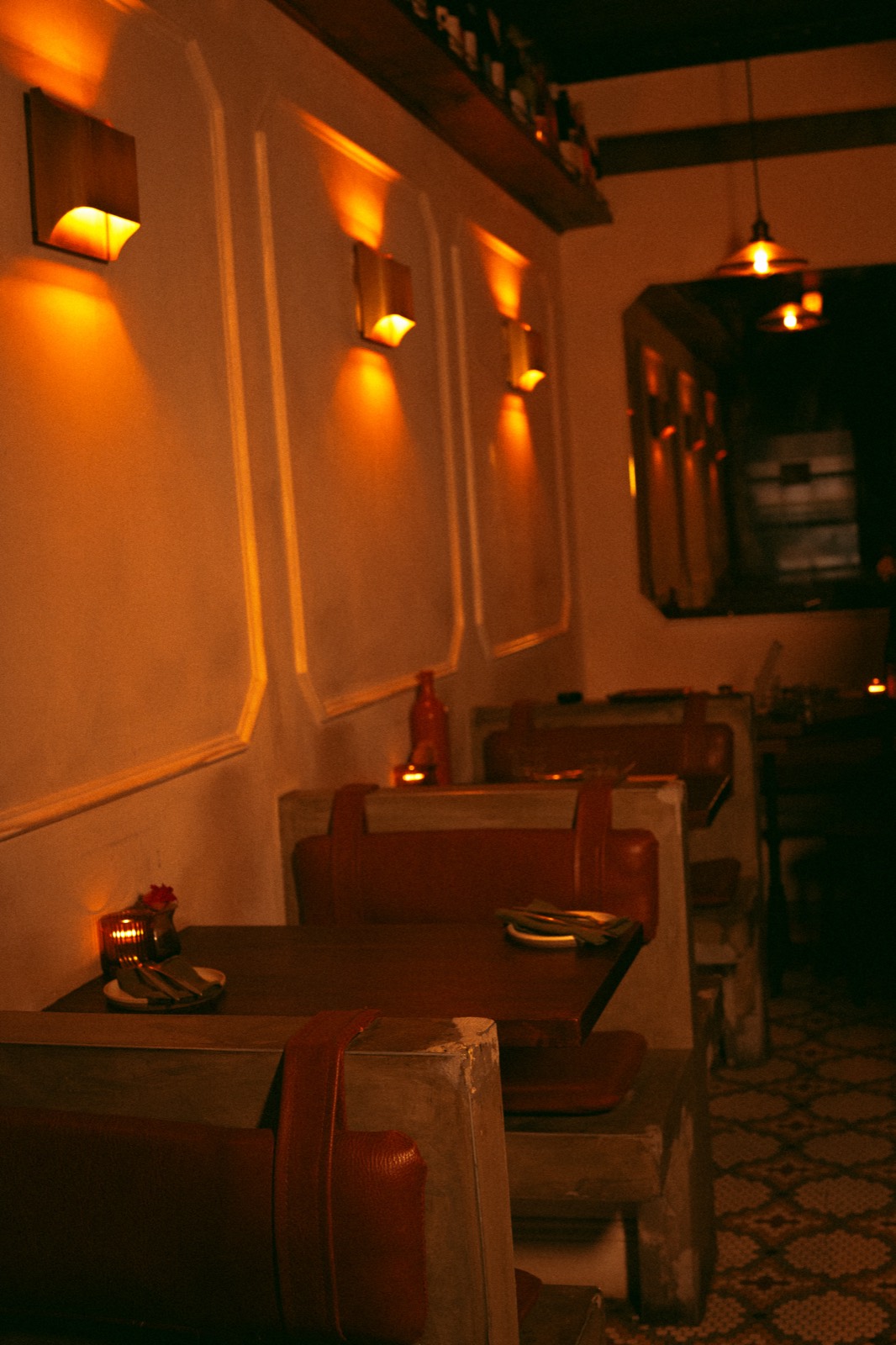 The candlelit 23-seat dining room at WEST10WEST with leather banquettes, wood tables and warm sconce lighting