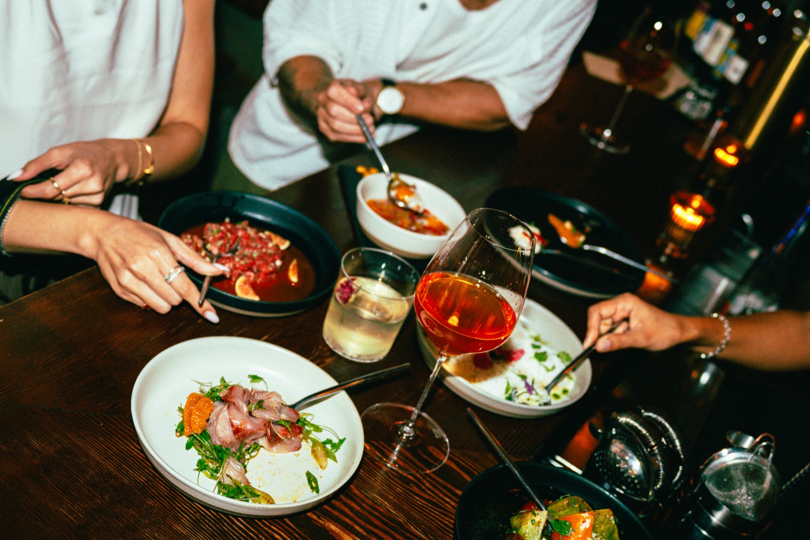 Friends sharing plates, natural wine and cocktails around a table at WEST10WEST in the West Village