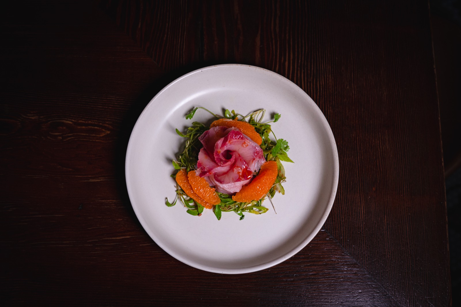 Overhead view of the hamachi crudo share plate on a dark wood table at WEST10WEST, West Village NYC