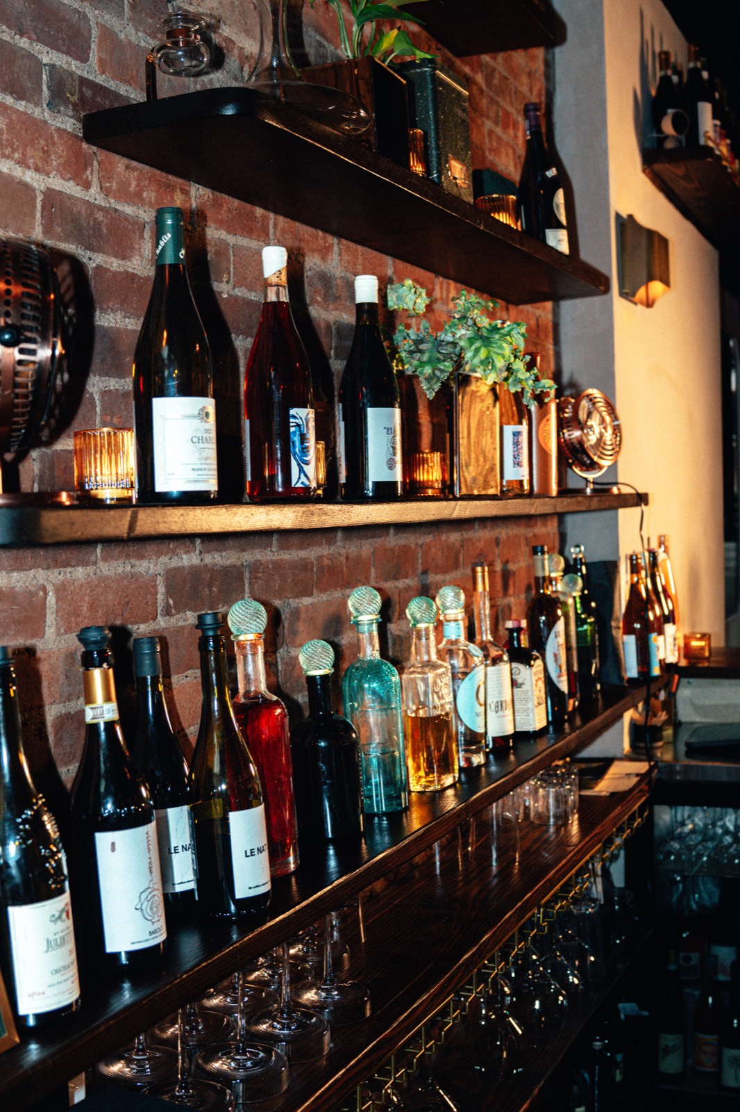 Natural wine and spirits on brick-backed shelves behind the bar at WEST10WEST, West Village wine bar