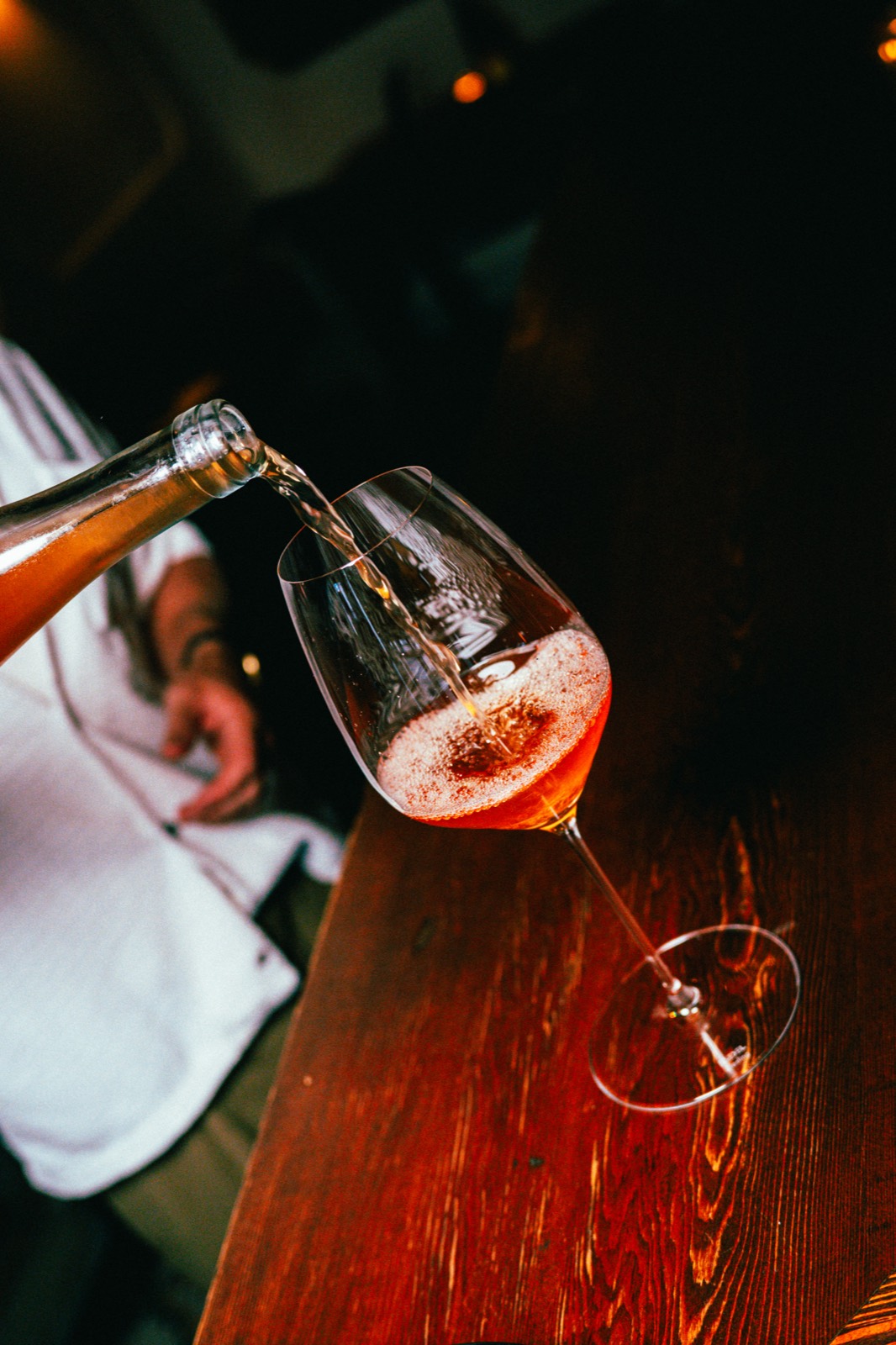 Pét-nat sparkling natural wine being poured into a stem at the bar of WEST10WEST, a natural wine restaurant in NYC's West Village