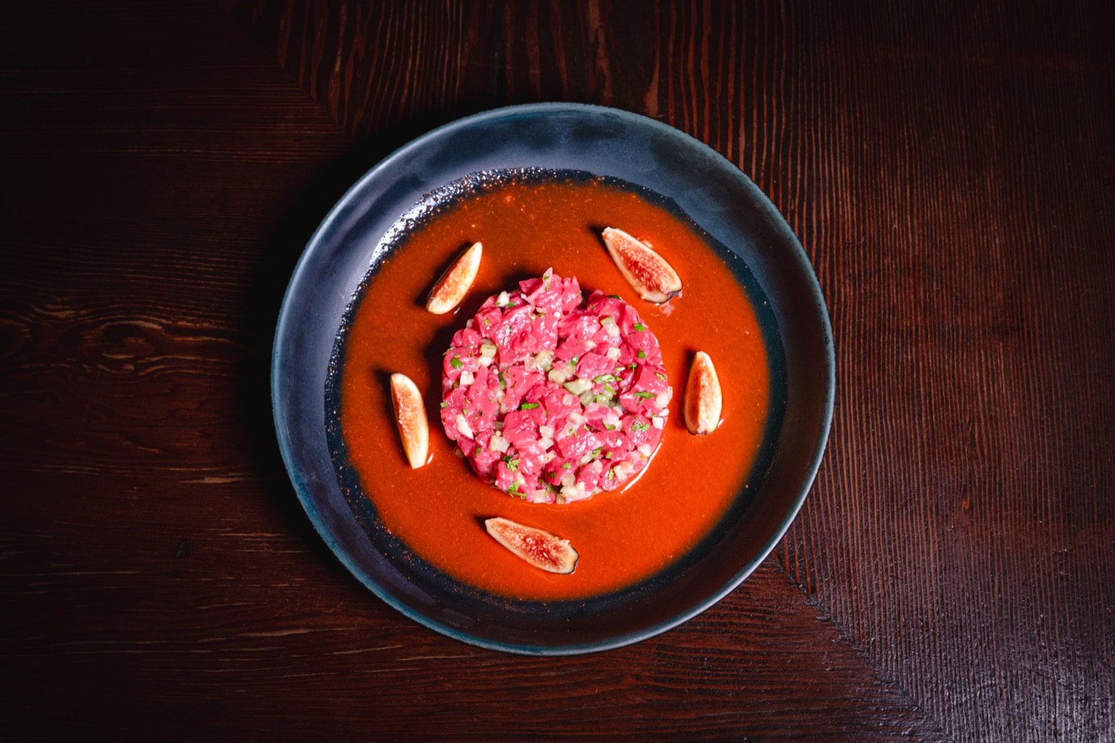 Torched wagyu share plate with fresh figs in a red pepper emulsion, served in a dark bowl at WEST10WEST