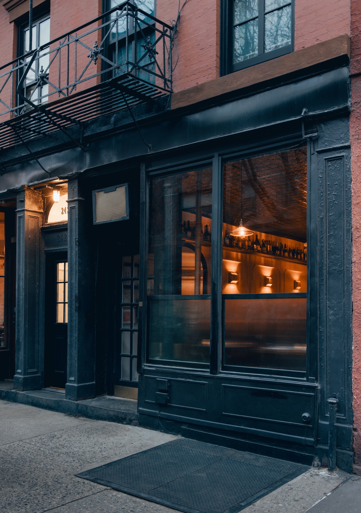242 West 10th Street at dusk, the bar glowing through the window